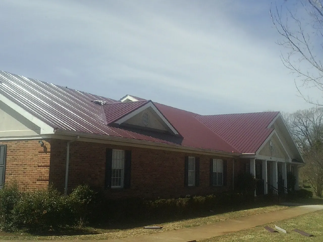 Red metal roof with gabled entries on a long brick building in Orient